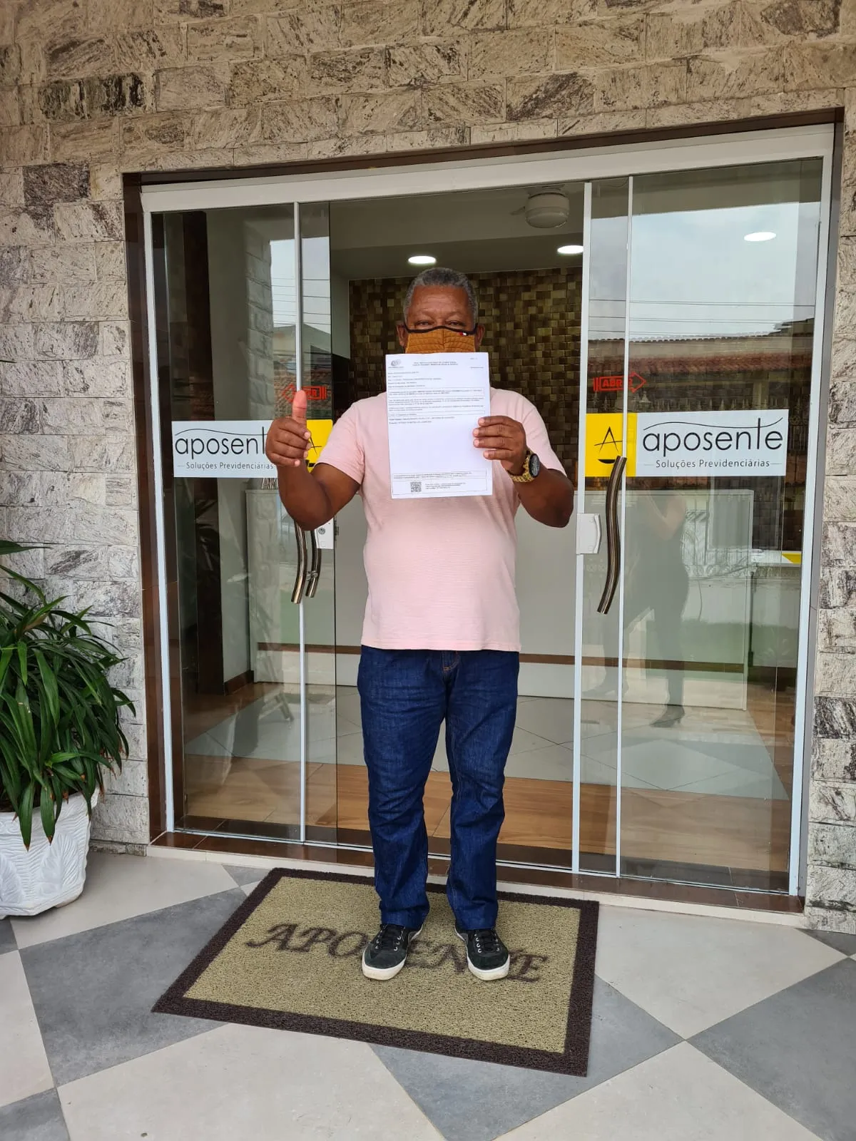 Cliente Aposente na fachada do escritório com documento